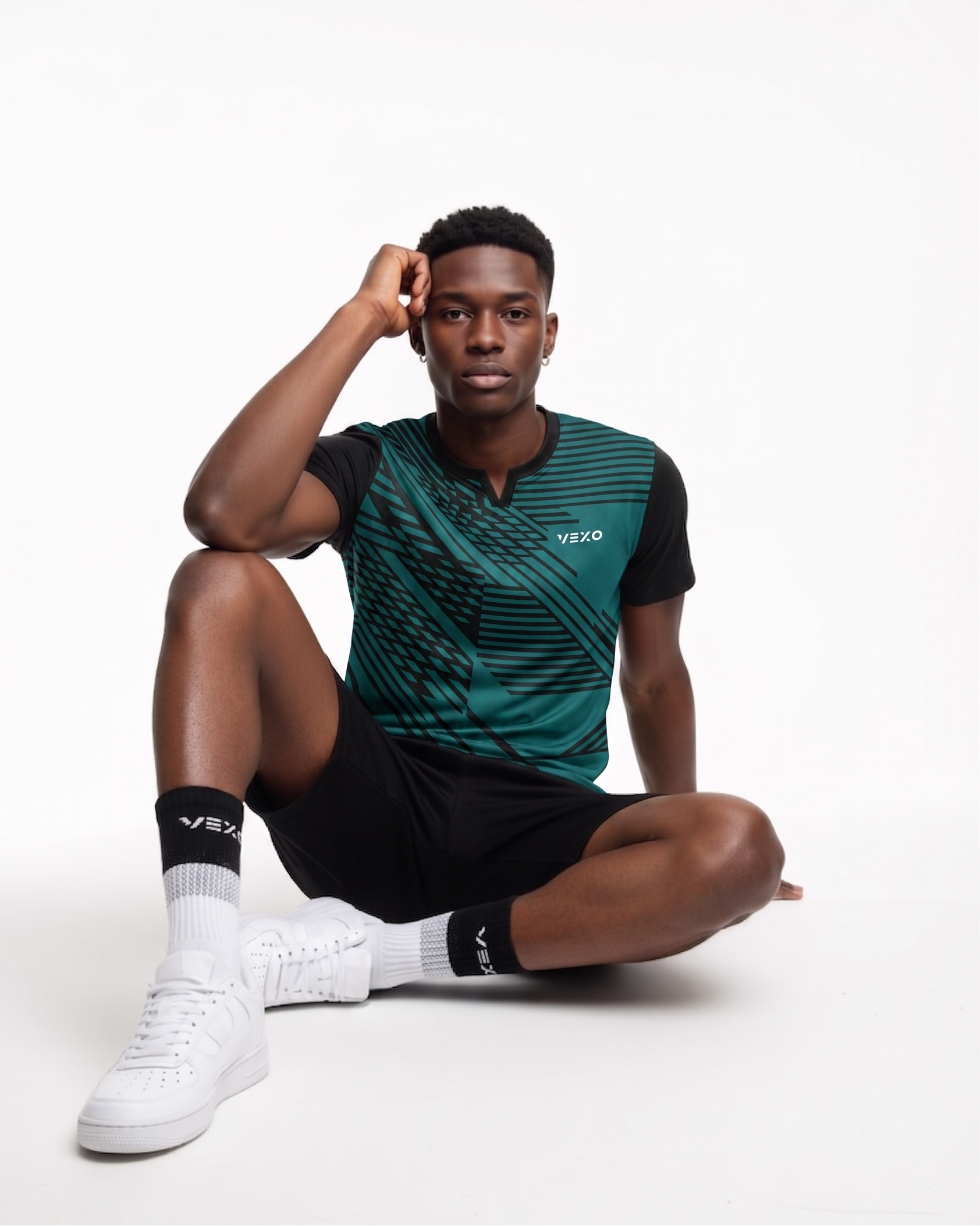 Model wearing VEXO athletic wear: teal geometric print t-shirt and black shorts. White sneakers & socks.